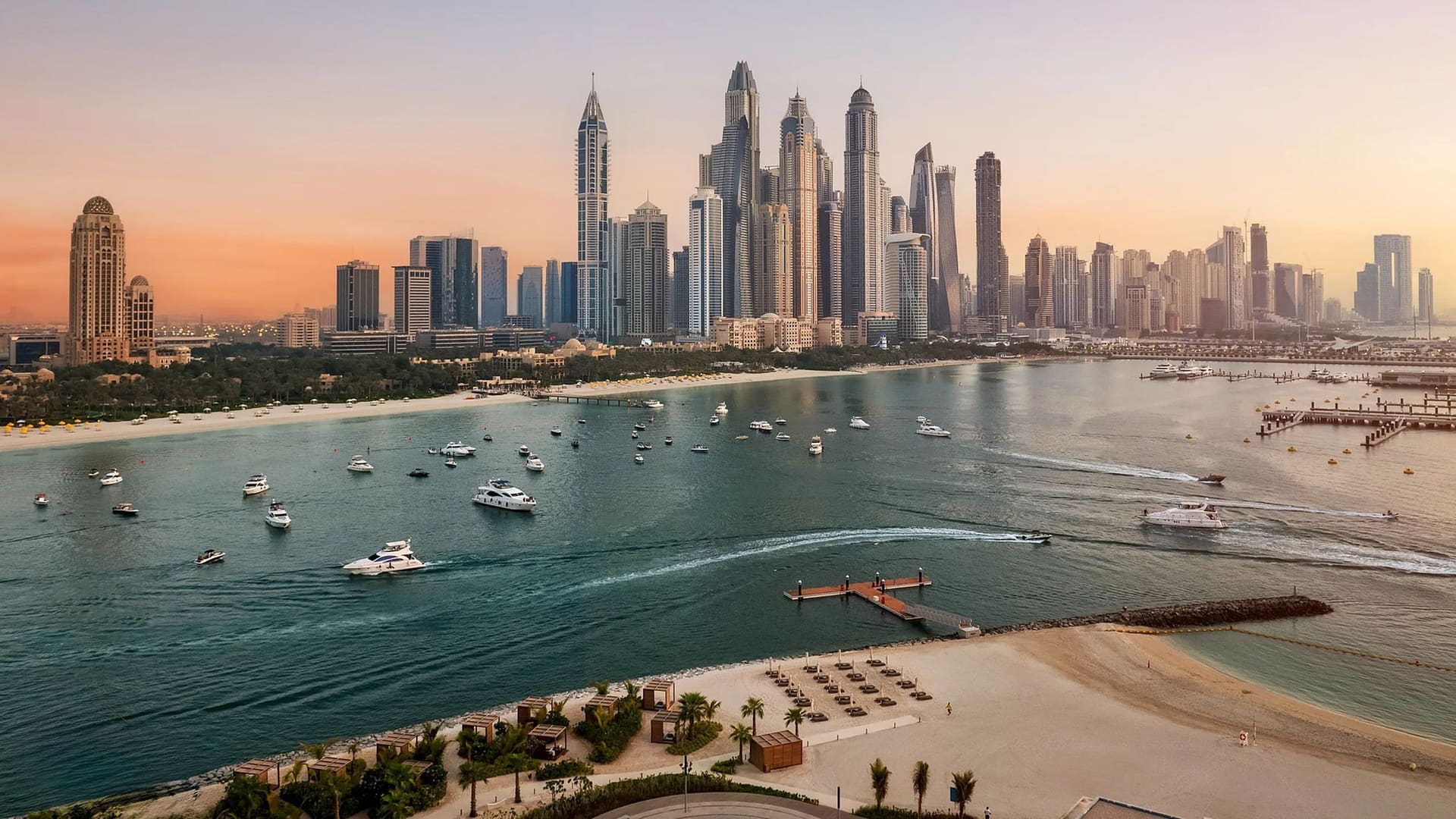 Dubai Marina skyline at sunset with beaches and yachts in the foreground